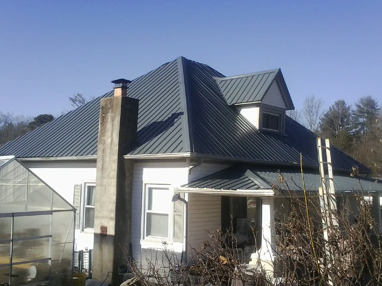 Dark blue standing seam metal roof on a white farmhouse with dormer — Slate & Tile Roof Repair by Roofing Brothers in Twin Falls