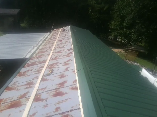 Old rusted panels beside newly installed green metal roofing — Wind Damage Roof Repair by Roofing Brothers in Twin Falls