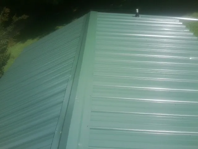New green metal panels meeting at the ridge of a roof — Flat Roof Repair work by our crew in Twin Falls