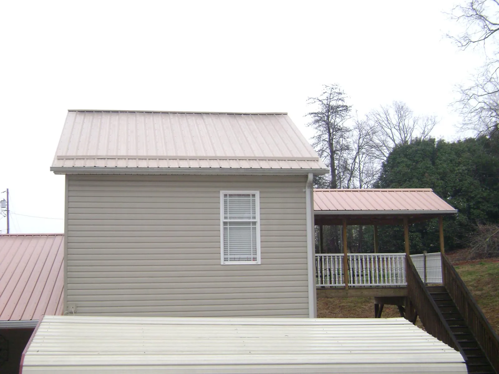 Tan metal roofs on a two story addition and attached porch, from a Roof Replacement job in Twin Falls