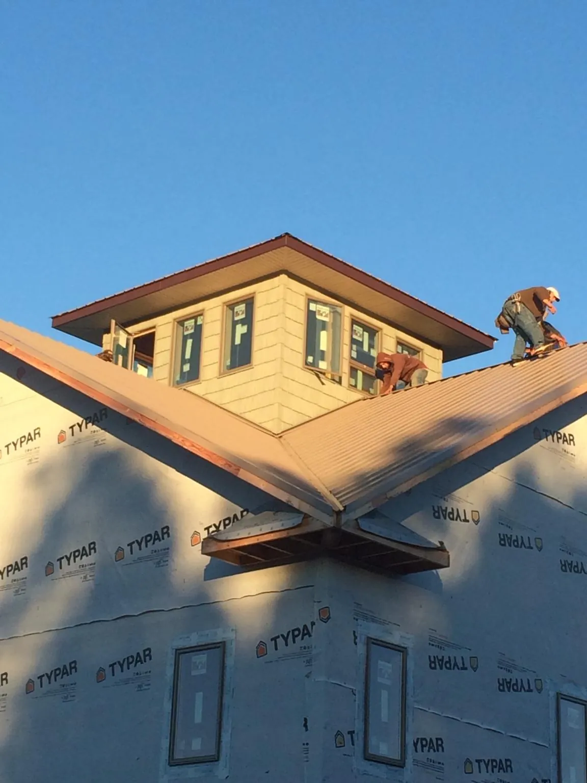 Roofers working around a rooftop cupola on a new metal roof at sunset — Roof Waterproofing in Twin Falls by Roofing Brothers